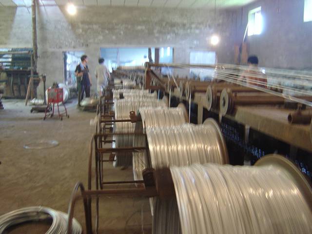 Several workers are operating galvanized binding wire machines.