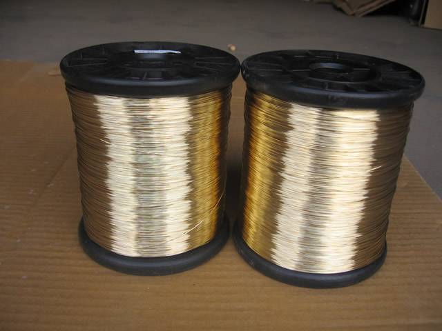 Two black spools of brass wire on the ground.