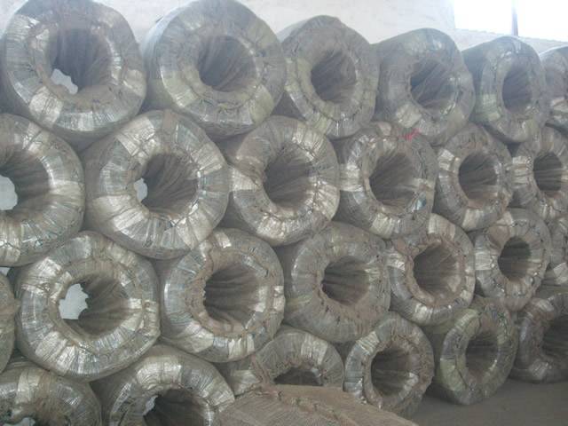 Several bi coils of PVC coated wire are piled on the ground.