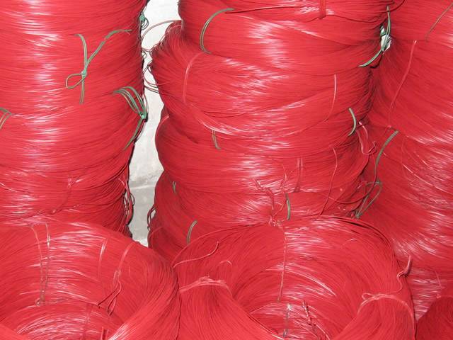 Several red color PVC coated wires are piled on the ground.