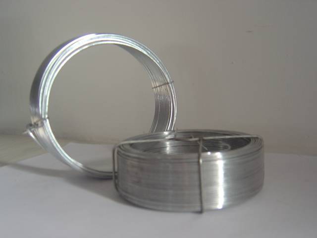 Two rolls of galvanized steel wire: one is standing and one is lying on the table.
